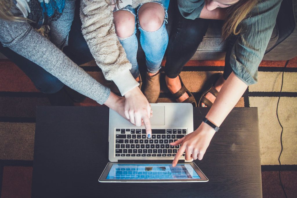 Grupo de Jovens vendo e apontando algo no computador
